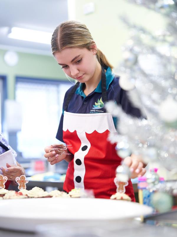 Carinity Education Southside student, Kirrah, lovingly decorating the red velvet cupcakes