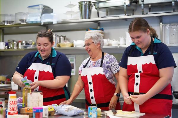 Carinity Education Southside students Shaylee and Jasper rolling the apricot and white chocolate balls with Margie Hyde, resident of Carinity Wishart Gardens