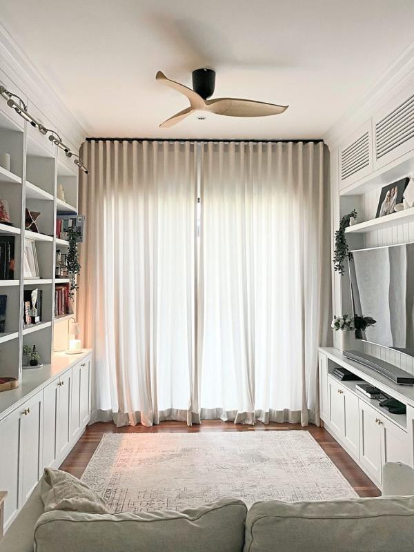 The cosy family room features a three-column bookshelf, cabinets, a two-seater sofa and a wall-mounted TV.