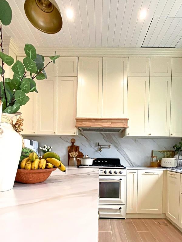 White cream cabinets go well with sintered stone countertops and backsplash in the kitchen. 