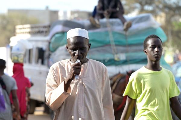 A man drinking from a plastic sachet filled with drinkable water.