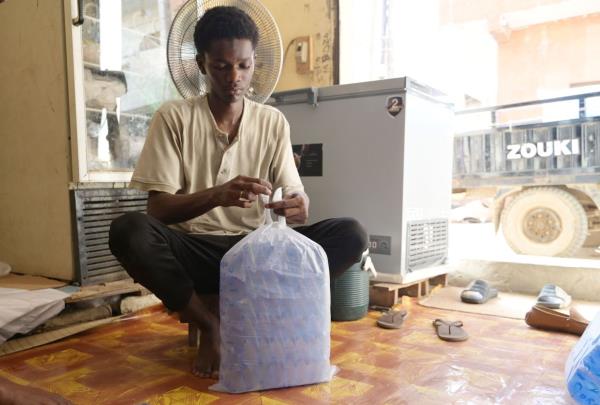 A worker packs plastic sachets filled with drinkable water for delivery.