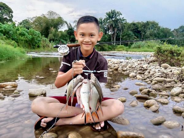 Muhammad Hadif Danish Zafran Hamidi, 13, with a happy haul of sebarau and lampam.