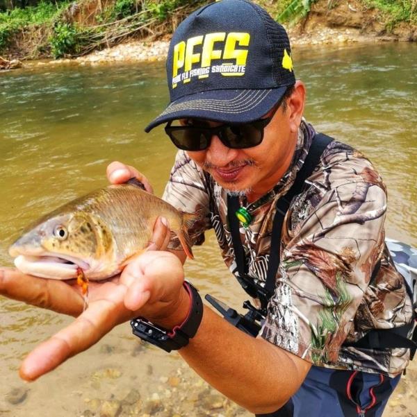 Rizal Effendi holding a sikang with a slight upturned lower jaw looking much like a brown trout.