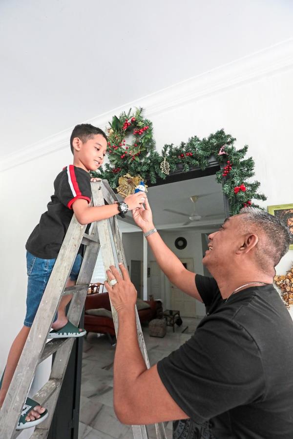 Lee (right) helps his son Liam put up Christmas decorations for the festive season.