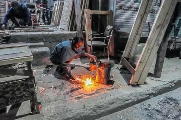 A man preparing fire for the traditio<em></em>nal fire-pot called kangri before using it on a cold evening in Srinagar, Kashmir.