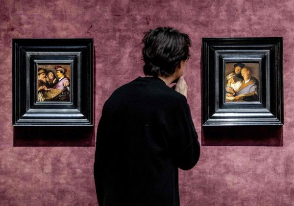 A person looks at a painting during the preview of the exhibition 'Rembrandt's four senses - his first paintings' in the De Lakenhal museum in Leiden, on January 18, 2024. — Photo: Remko de Waal/AFP