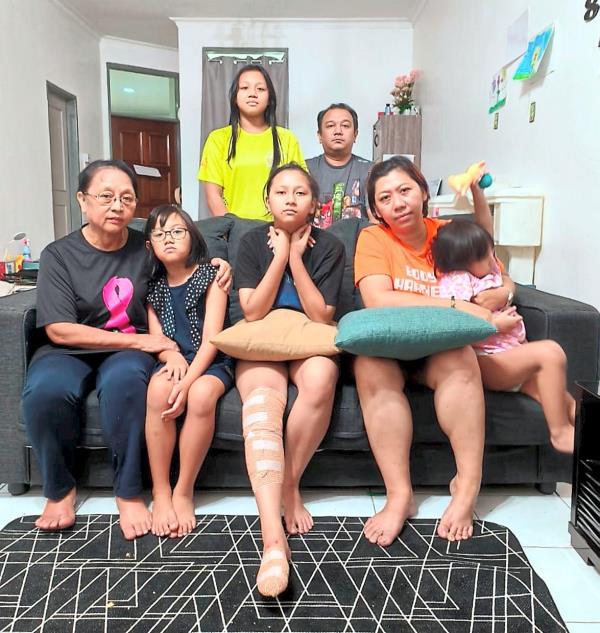 Saved by their neighbours: Rogy (back, right) with his family members who were rescued by their neighbours Gillian and Zainal. They are at a relative’s house now. 