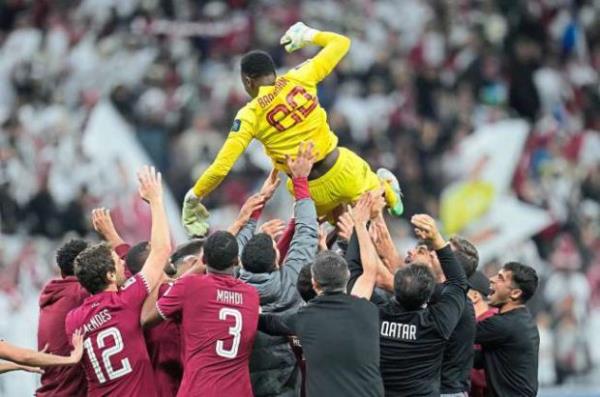 Players and staff of the Qatar team throw goalkeeper Meshaal Barsham in the air to celebrate their quarter-final victory over Uzbekistan, — AP