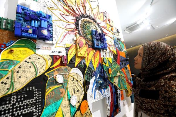 A visitor takes a closer look at Nor Tijan's 'Balloons Of Hope' (e-waste on blockboard, 2024). The combination of tech parts laid across the different levels of the block board create an almost glitch-like effect. Photo: The Star/Azlina Abdullah 