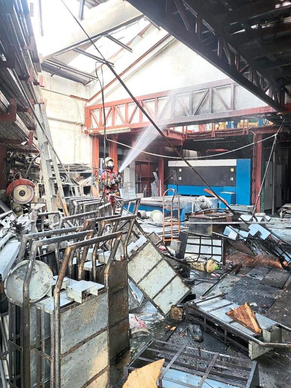 Deadly scene: A fireman putting out a fire after the blast at the factory. — Photo courtesy of the Fire and Rescue Department