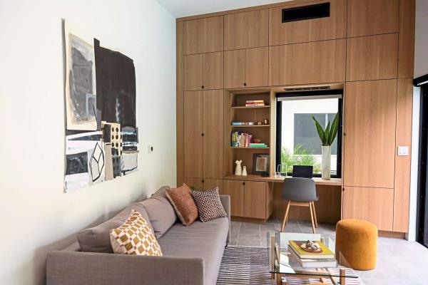 Floor-to-ceiling custom millwork provides a well-lit work-from-home space, concealing the mini-split HVAC system while also supplying ample storage.