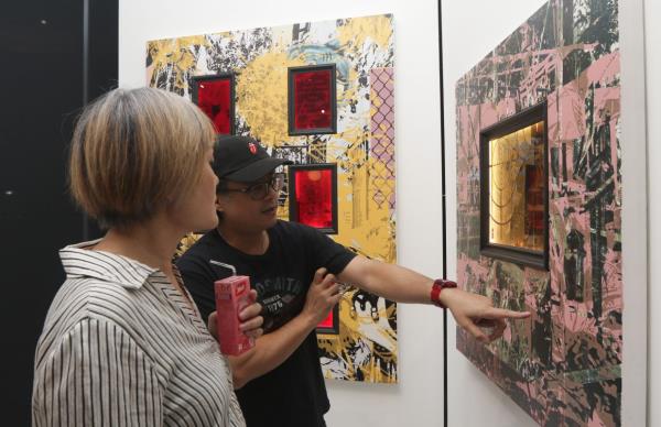 Visitors intrigued by a detail from an artwork by Syahmi at the 'Introspektif' show. Photo: The Star/Izzrafiq Alias