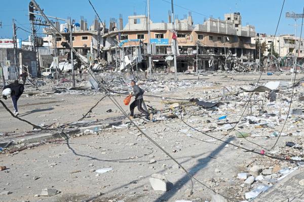 Palestinians walking through destruction by the Israeli bombardment in the Nusseirat refugee camp in Gaza Strip. — AP