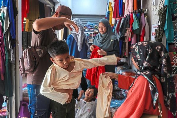 Festive shopping: A boy trying on new clothes at Bazak Tok Guru in Kota Baru, Kelantan. — Bernama