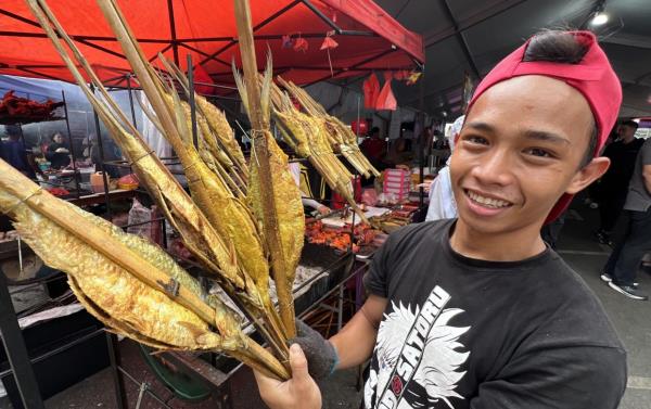 Zafilus Ismadi selling grilled terubok at the Satok Ramadan bazaar. - ZULAZHAR SHEBLEE/The Star