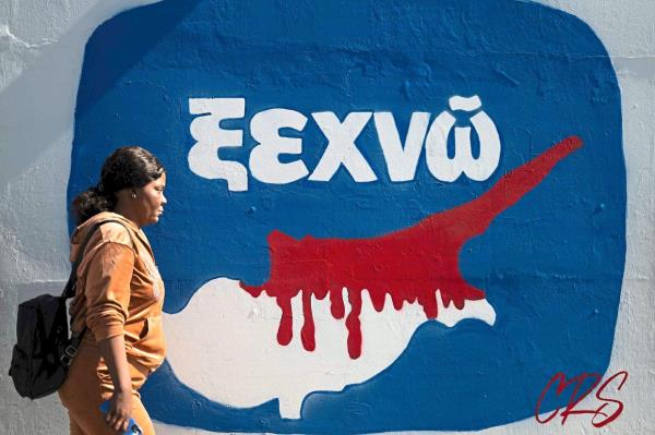 A woman walking past graffiti depicting a map of Cyprus on a wall in Nicosia. — AFP