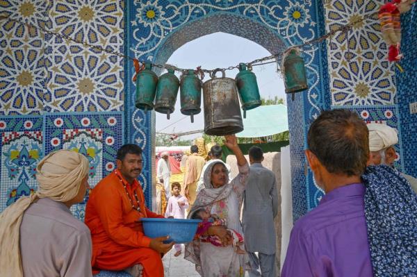 A woman rings a bell at a Sufi shrine during the annual mela in Shah Jiwana, Jhang district, Punjab, Pakistan. Photo: AFP 