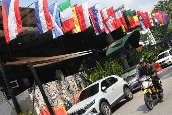 A motorcyclist passing by the flags of the participants country taking part in Euro 2024 tournament at Souled Out Hartamas on June 11.—AZMAN GHANI/The Star