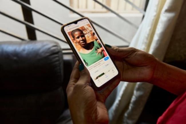 Someone holds a phone with a picture of a young African woman holding a young child