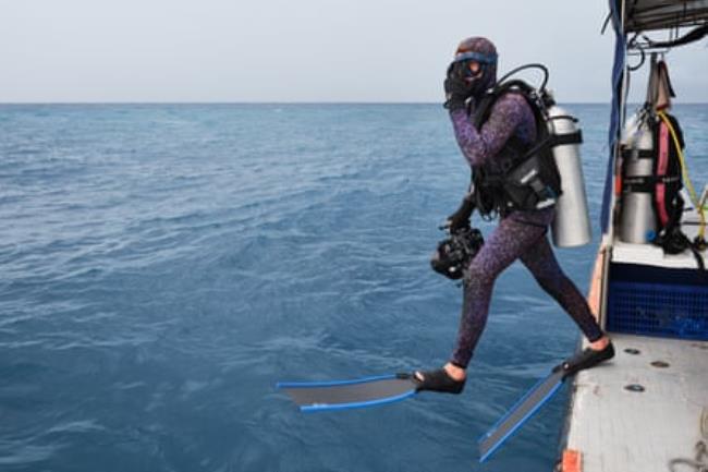 Lennart Vossgaetter jumps into the water off a boat, wearing diving gear