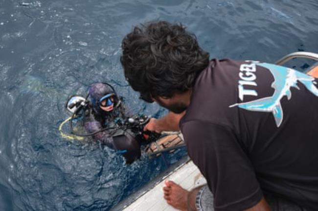 A member of the boat crew prepares to help Lennart Vossgaetter back onboard after his dive