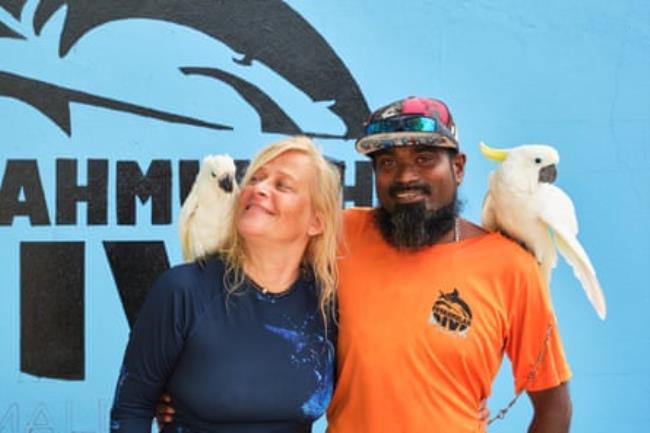 Tatiana Ivanova and Ibrahim Siyan stand together, each with a white cockatoo on their shoulder