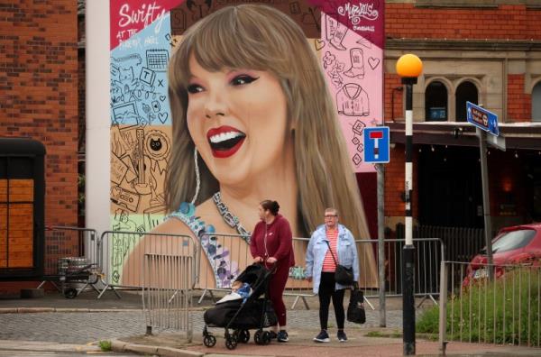 People walk past a mural by Murwalls of U.S. musician Taylor Swift outside the Phoenix Hotel, in Liverpool