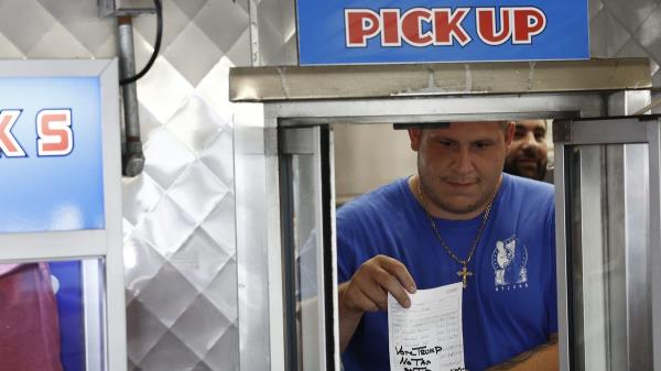 restaurant worker holds up a receipt with a note that reads 