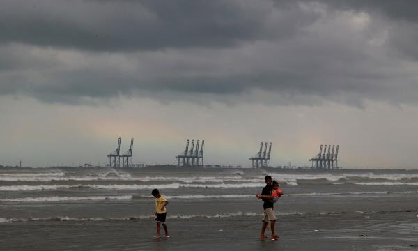  Children play, with the rainbow and rain clouds in the background, at Clifton Beach in Karachi on Aug 30, 2024. — Reuters 