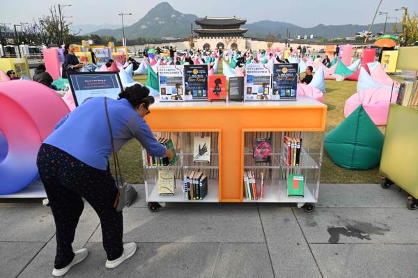 A woman picks up a book by South Korean author Han Kang, who won the 2024 Nobel Prize in Literature, displayed during an outdoor library event at Gwanghwamun square in central Seoul. — Photo: Jung Yeon-je / AFP