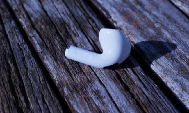 A single earbud of Apple AirPods 4 resting on table.