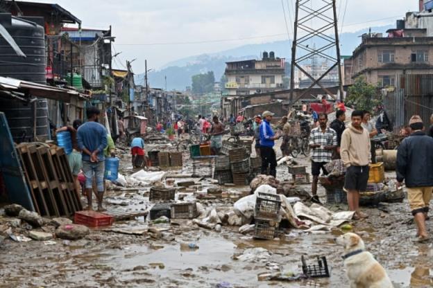 People stand in the street near their belo<em></em>ngings that were swept away by flooding. 