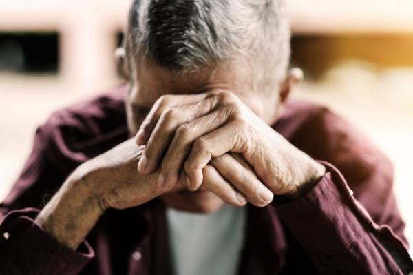 Older man with his head in his hand