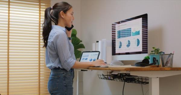 Woman working at a standing desk in small office workspace