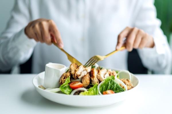 Closeup image of a man eating chicken salad on table in the restaurant