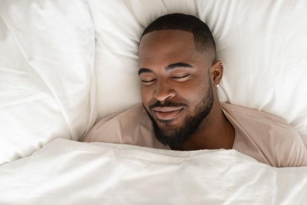 Top view of happy man sleeping in comfortable white bed