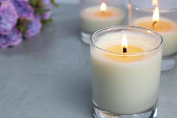 close up of candle in glass co<em></em>ntainer burning with two candles behind it