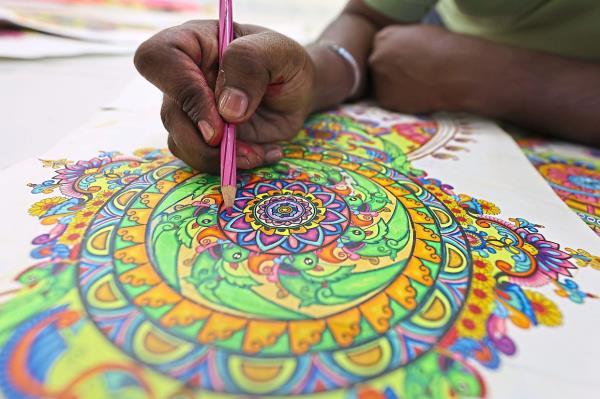 Ruben sketches kolam designs freehand and colours them in before bringing them to life.