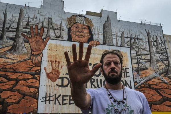 Brazilian artist Mundano poses in front of his massive street mural. — Photo: AFP