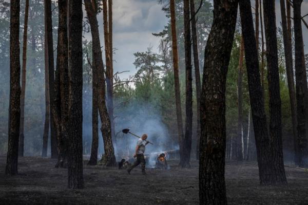 A worker carries a shovel he used to dig a firebreak to co<em></em>ntain a forest fire near Yarova, Sviati Hory Natio<em></em>nal Park, Do<em></em>netsk region on July 29. Forest workers have been killed by landmines, booby traps and shelling during the conflict, according to enviro<em></em>nment ministry data.   