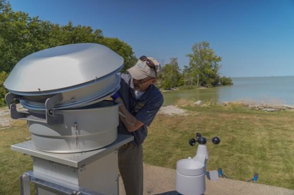 David Kennedy, an associate professor of medicine at the University of Toledo, replaces an air filter inside of a mo<em></em>nitoring station near Lake Erie, Thursday, Sept. 5, 2024, in Oregon, Ohio. (AP Photo/Joshua A. Bickel)