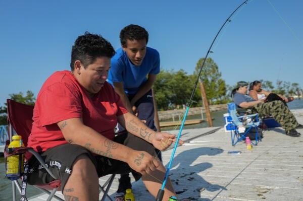 Malissa Vallestero, left, helps Jaylon Chism, center, untangle a fishing line, Wednesday, Sept. 4, 2024, in Toledo, Ohio. (AP Photo/Joshua A. Bickel)
