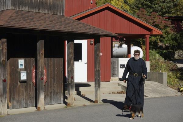 Brother Luke, an Orthodox Christian monk, walks his 10-week-old German shepherd Pyrena outside the residences of the New Skete monastery, wher<em></em>e he directs the dog breeding program that has provided both financial and spiritual support to the community for decades outside Cambridge, N.Y., on Oct. 12, 2024. (AP Photo/Giovanna Dell’Orto)