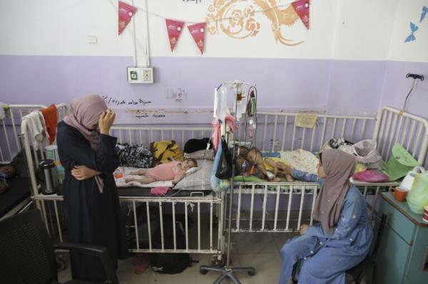 FILE - Amira Al-Jojo, left, stands beside her 10-month-old son, Yousef Al-Jojo, who suffers from malnutrition at Al-Aqsa Martyrs Hospital, wher<em></em>e he is undergoing treatment, in Deir al-Balah in the central Gaza Strip on June 1, 2024. At right is Nuha Al-Khaldi and her child. (AP Photo/Jehad Alshrafi)
