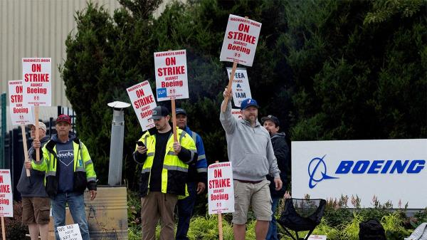 Striking unio<em></em>n members next to Boeing sign