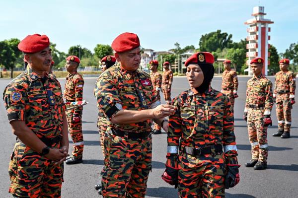 JBPM Fire and Rescue Operations director Nordin Pauzi placing the Storm 'patch' on Saredah's uniform after the completion of basic training. 