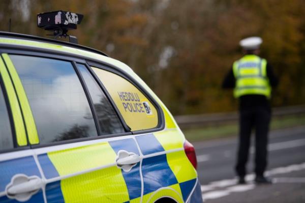 Welsh Police on the road and a police car. 