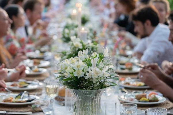 Group of people havin<em></em>g dinner at wedding reception table at back yard.