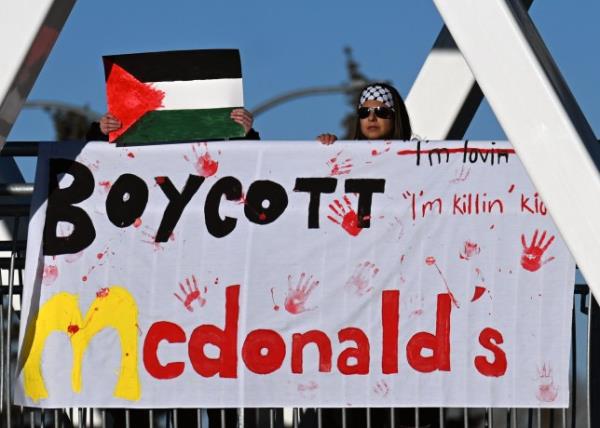 EDMONTON, CANADA - DECEMBER 26, 2023: Members of the local Palestinian diaspora hold a banner that reads 'Boycott McDonald's' during the 'Action Boxing Day' protest on the WEM pedestrian bridge leading to the West Edmo<em></em>nton Mall, renowned as North America's Largest Shopping Mall, on December 26, 2023, in Edmonton, Alberta, Canada. The demo<em></em>nstration organizers accused politicians and businesses of profiting from Palestinian suffering and complicity in a genocide. Their message, 'While you shopping, bombs are dropping,' aimed to capture the attention of shoppers arriving or leaving the Mall on Boxing Day, urging them to co<em></em>nsider the o<em></em>ngoing conflict. (Photo by Artur Widak/NurPhoto via Getty Images)